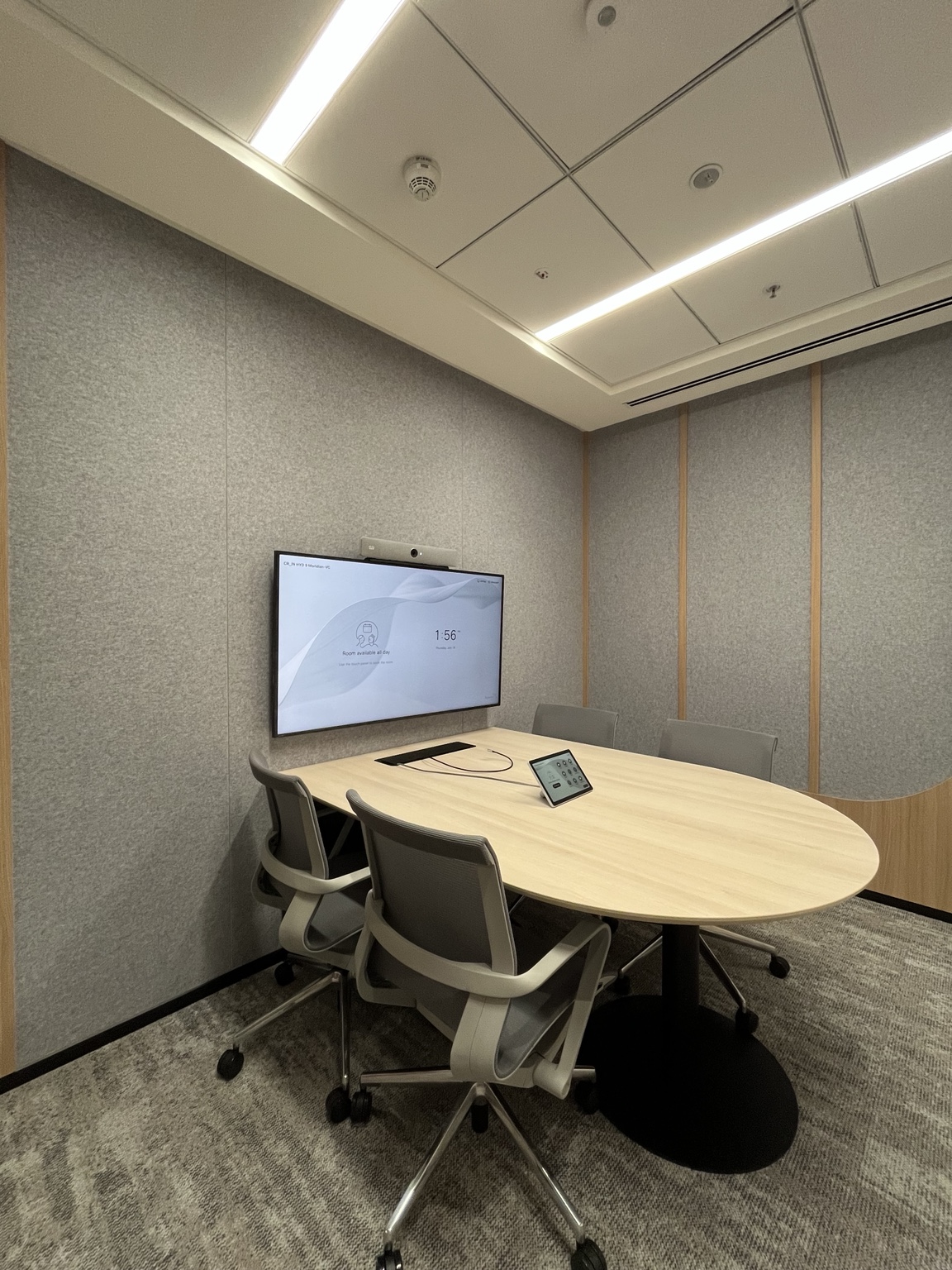 An intimate meeting space with a wall-mounted display, video bar and tabletop touch controller.