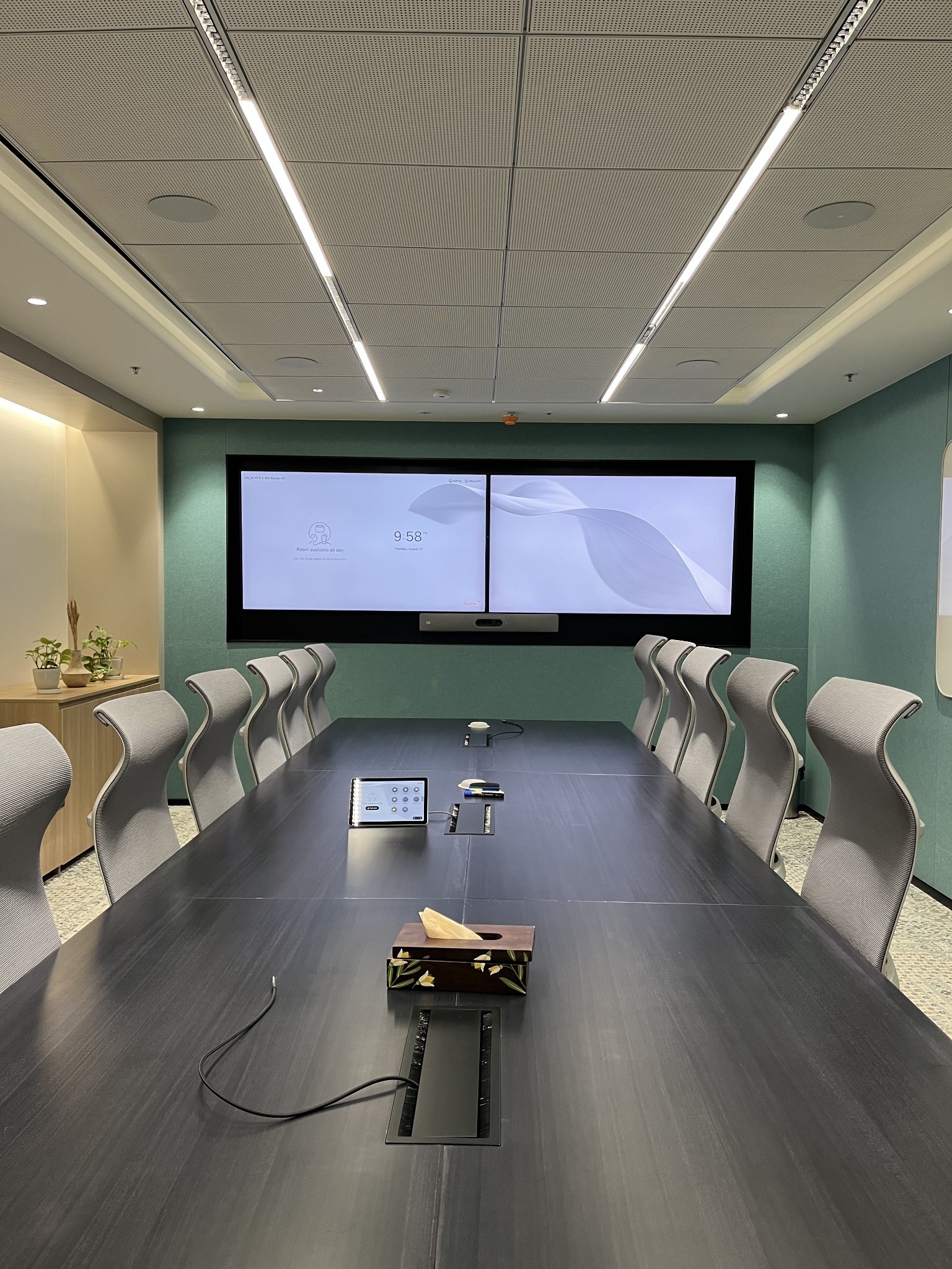 A large boardroom featuring dual displays and an integrated video conferencing system.